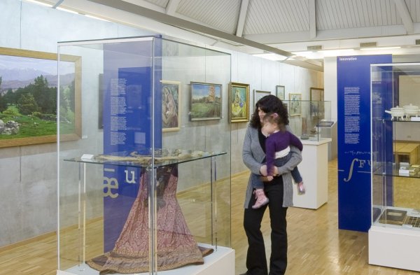 Eine Frau mit Kind auf dem Arm betrachtet ein Ausstellungsstück im Museum